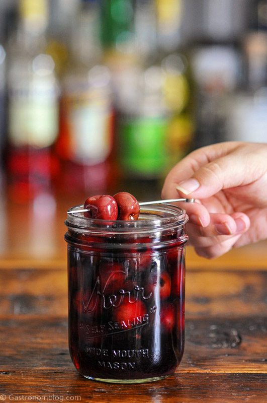 Bourbon cherries on cocktail pick and in jar with red liquid