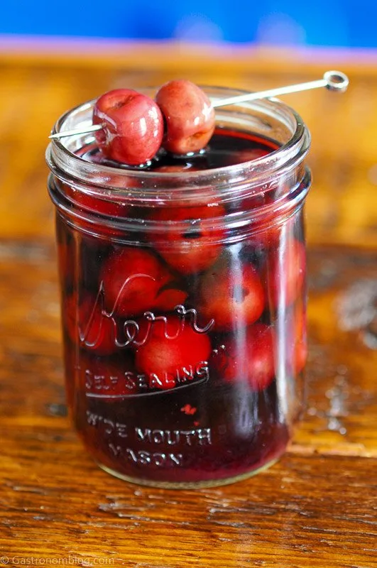 Red cherries on cocktail pick, and in jar with red liquid