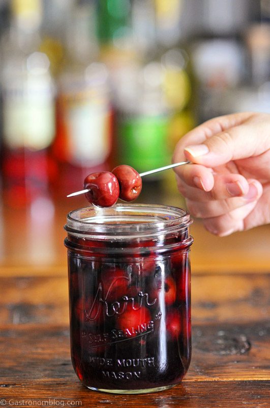 Bourbon cherries on cocktail pick and in jar with red liquid