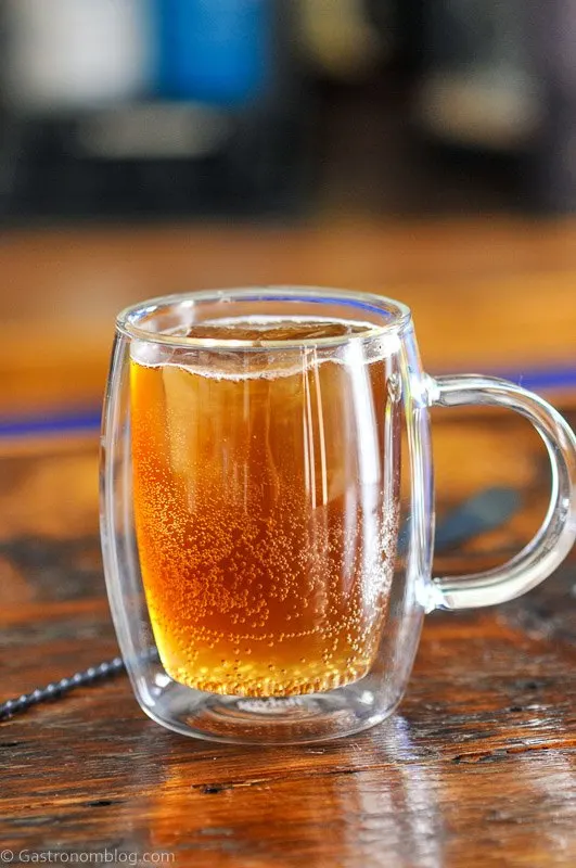 Brown coffee tonic in glass mug with handle and clear ice cube