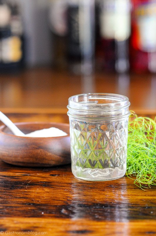 syrup in jar with fennel fronds, wooden bowl of sugar