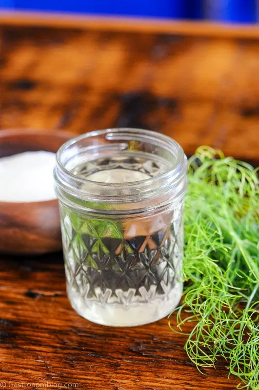 syrup in jar with fennel fronds, wooden bowl of sugar