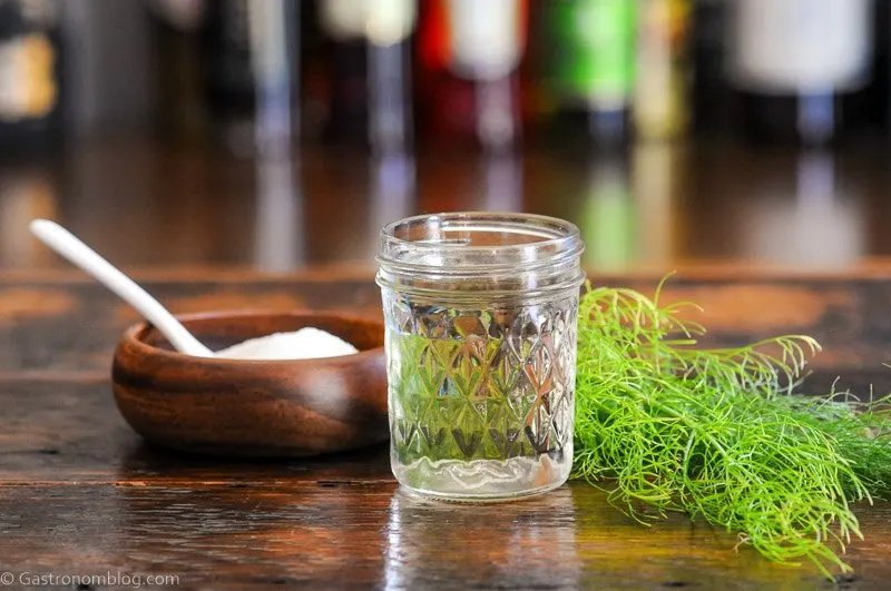 syrup in jar with fennel fronds, wooden bowl of sugar