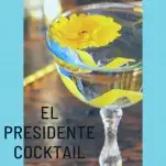 El Presidente Cocktail in blue tinted coupe, lemon peel and yellow flower on top