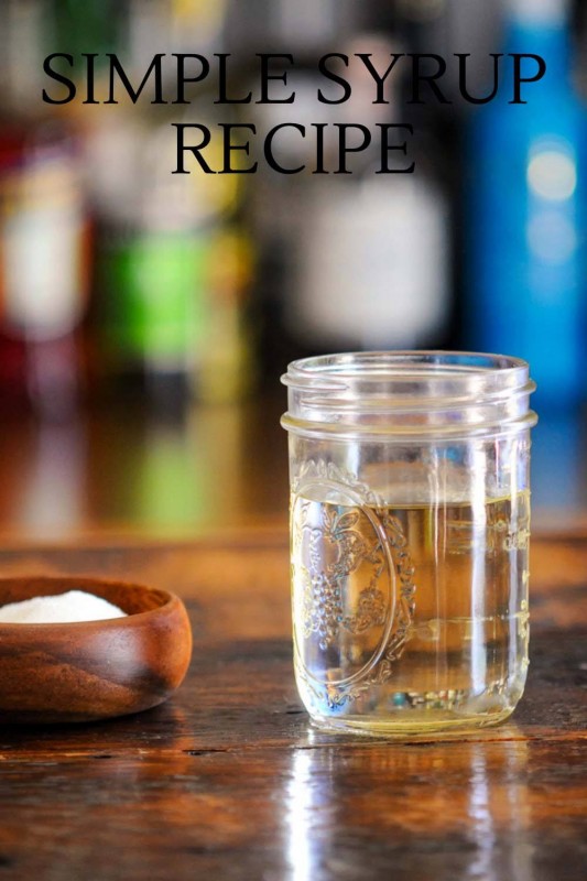 Clear syrup in mason jar, wood bowl with sugar and white spoon