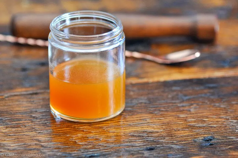 Apple Cider Simple Syrup, orange syrup in jar, gold spoon behind, on wooden table