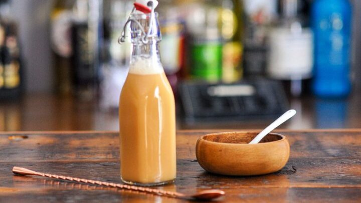 Tan liqueur in a swingtop bottle, a Salted Caramel Vodka has a wooden bowl of salt next to it with a white spoon