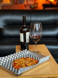 Pizza on silver tray lined with paper, wine glass and wine bottle behind at Solera wine bar