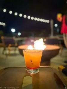 orange cocktail on table, fire behind at Hotel Grinnell