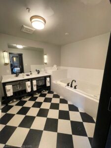 Bathtub and sinks in room with black and white check tile floor