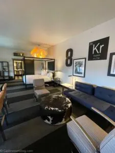 Sitting area of blue couch, gray chairs and bed in background at hotel Grinnell in Grinnell, Iowa