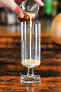 caramel vodka being poured into glass from jigger