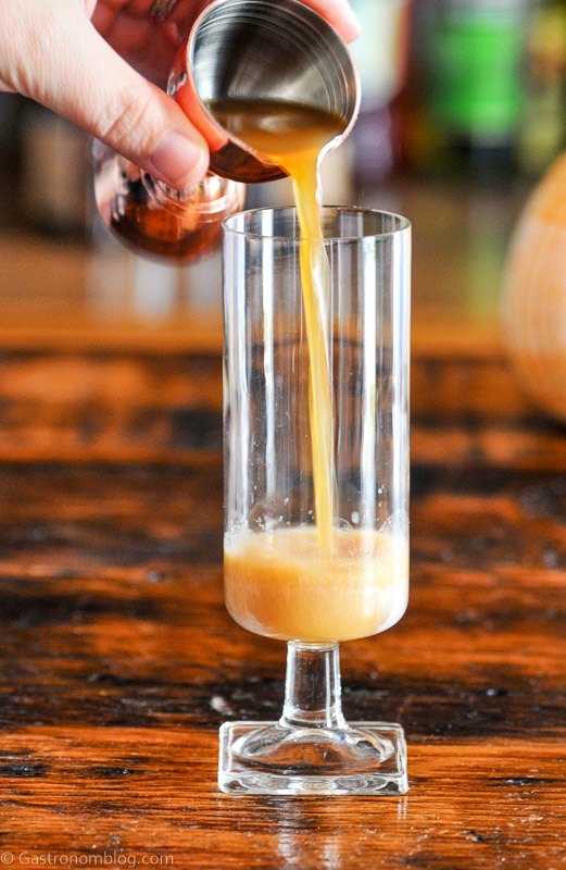 apple cider being poured into glass from jigger