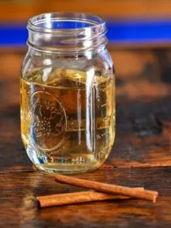 light tan colored cinnamon simple syrup in a jar on a wood table