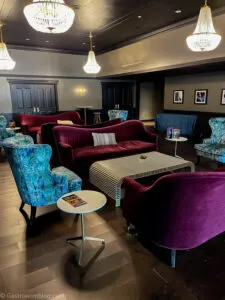 lobby at Highlander Hotel with maroon sofas, blue chairs, marble end tables and coffee tables