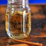 light tan colored cinnamon simple syrup in a jar on a wood table