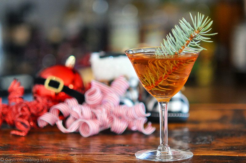 Brown cocktail, Mistletoe Martini, pine sprig in cocktail, Christmas decor behind