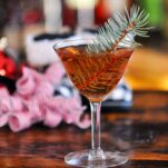 Brown cocktail, Mistletoe Martini, pine sprig in cocktail, Christmas decor behind