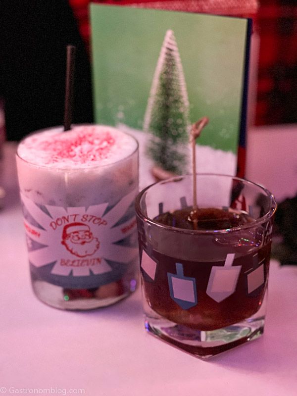 Blue cocktail with white foam, brown cocktail in dreidl glass at Mercury Omaha Christmas Pop Up Bar