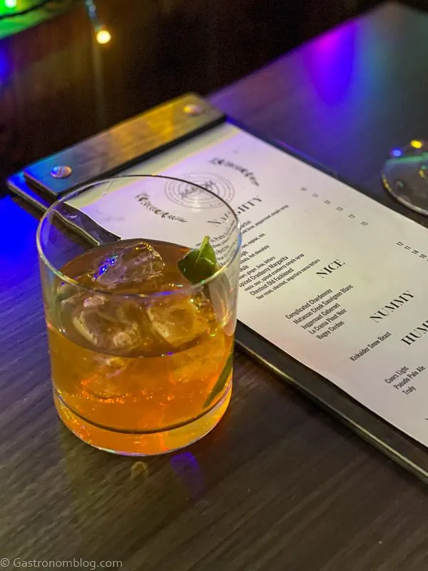 tan cocktail in rocks glass, menu next to cocktail