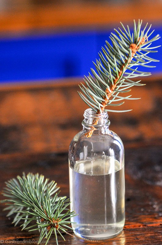 Pine Simple Syrup in small jar with pine sprigs in jar and beside jar