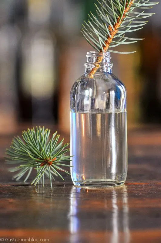 Syrup in small jar with pine sprigs in jar and beside jar