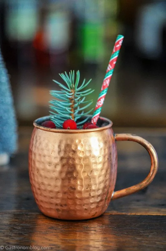 Yule Mule cocktail in copper mug with Christmas straw, cranberries and pine garnish