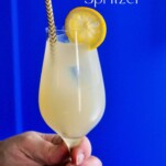 Yellow lemon non alcoholic spritzer ocktail in wine glass with straw and lemon wheel