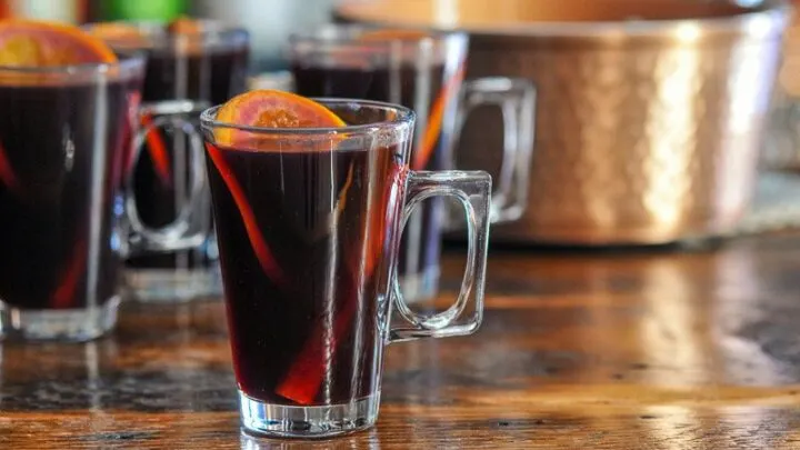 Red juice non alcoholic mulled wine in glass mugs with orange slices