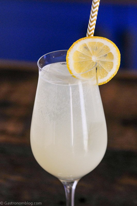 Yellow lemon non alcoholic spritzer cocktail in wine glass with straw and lemon wheel