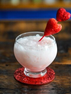 Pink cocktail with strawberry on heart pick, this Strawberry Vodka Cocktail