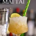 Winter Mai Tai cocktail, a gold cocktail in glass with pebble ice and bamboo straws, glass shaker behind