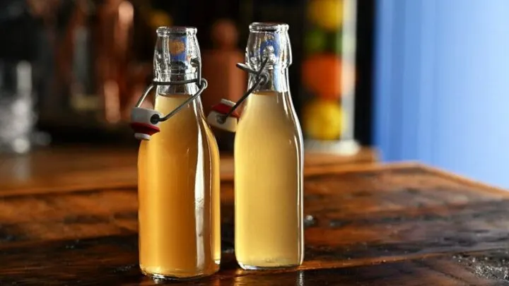 two bottles with light tan peach liqueur on a wooden table