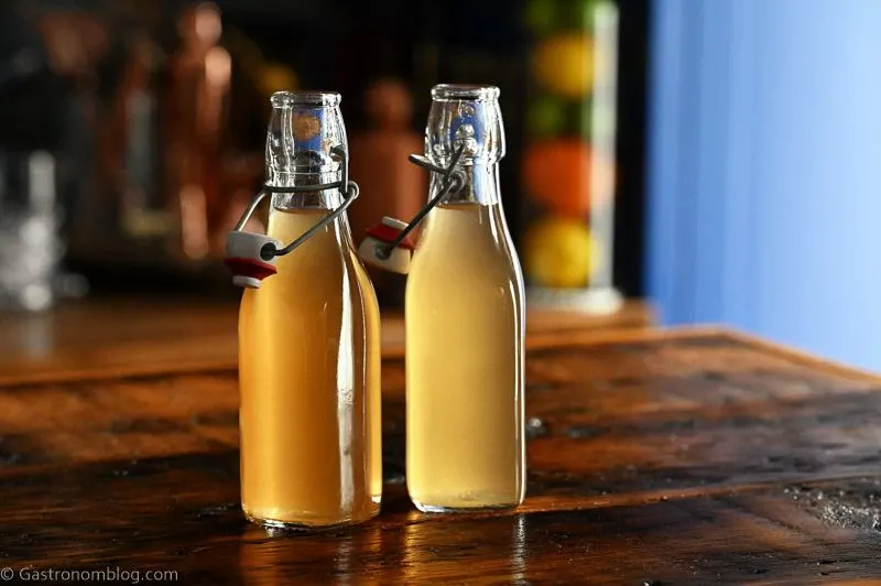 two bottles with light tan peach liqueur on a wooden table