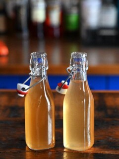 two bottles with light tan peach liqueur on a wooden table