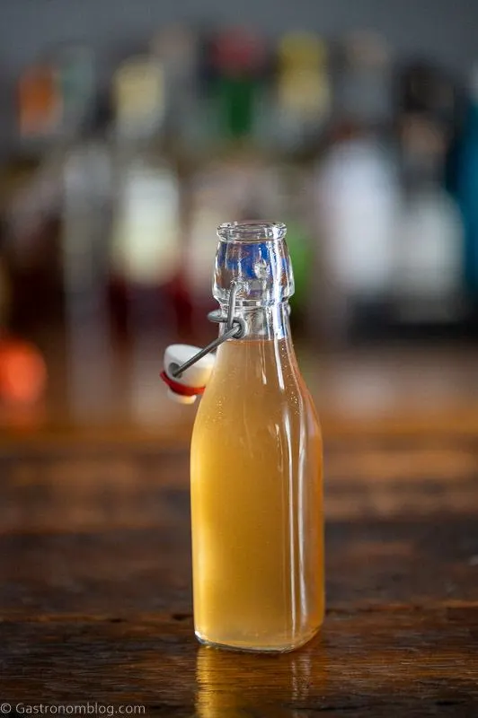 Bottle with light tan peach liqueur on a wooden table