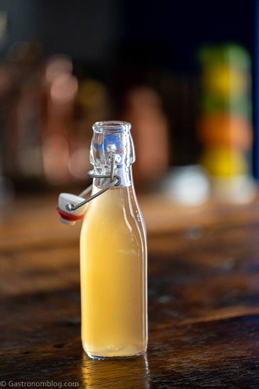 Bottle with light tan peach liqueur on a wooden table