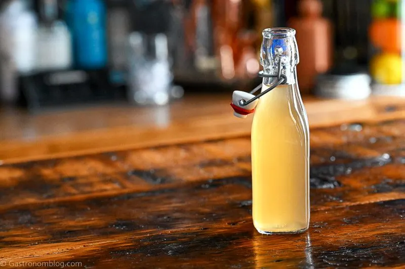 Bottle with light tan peach liqueur on a wooden table