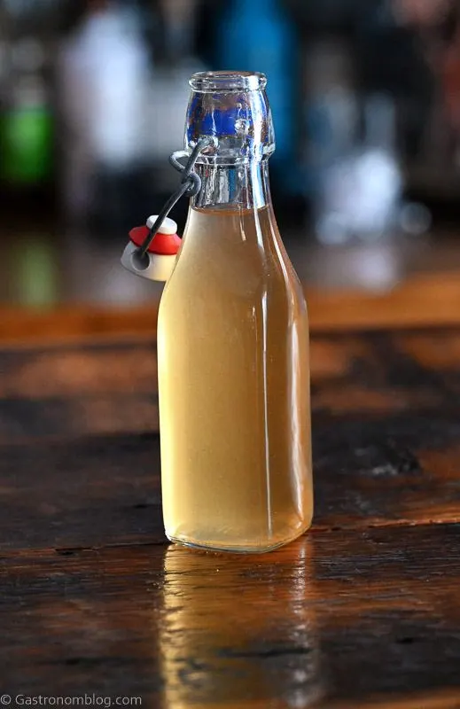 Bottle with light tan peach liqueur on a wooden table