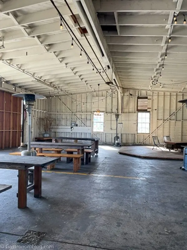 Inside of Humboldt Bay Social Club hangar, white painted walls, tables and bar stools