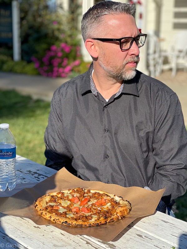 man in gray shirt and glasses with pizza on parchment in front of him