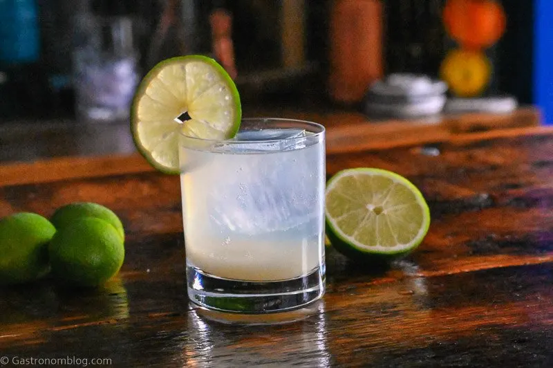 Opaque cocktail in rocks glass, lime wheel on glass, limes in background