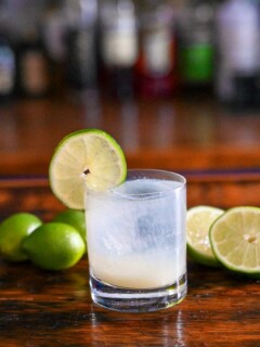 Opaque cocktail in rocks glass, lime wheel on glass, limes in background