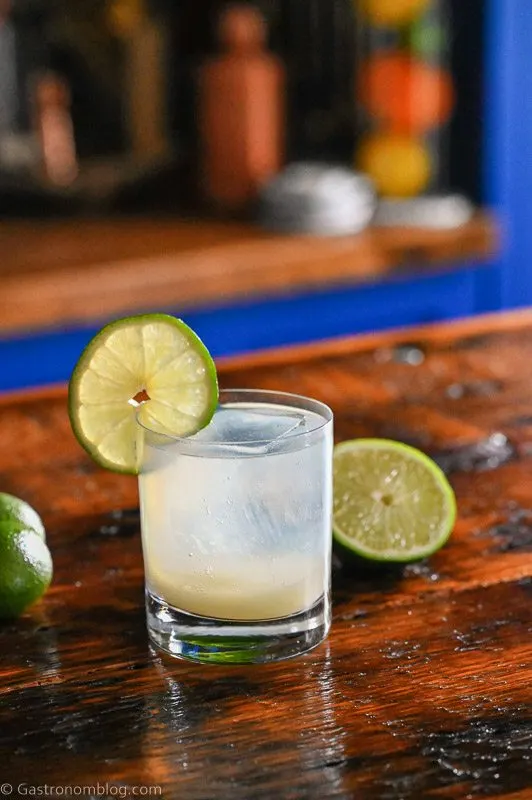 Opaque cocktail in rocks glass, lime wheel on glass, limes in background