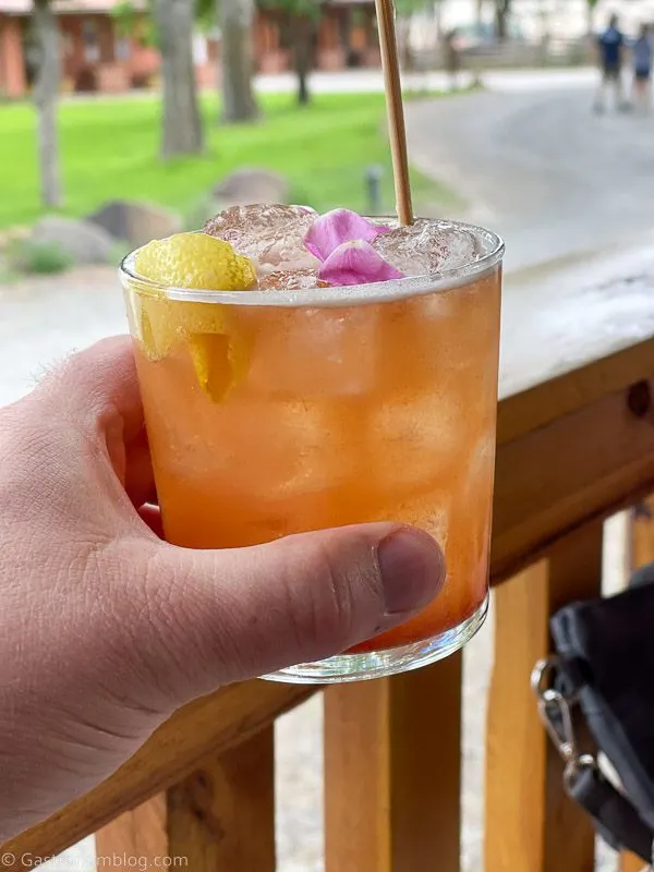 orange cocktail held by hand with rose petals at Hell's Backbone Grill