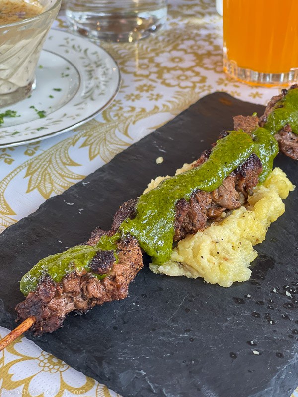 Beef skewer on polenta with green sauce on a slate plate at Hell's Backbone Grill