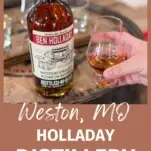 Hand holding whiskey tasting glass next to bottle of Ben Holladay Bourbon