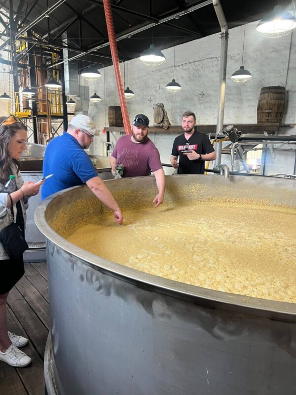 Men putting fingers into mash at Hollday Distillery