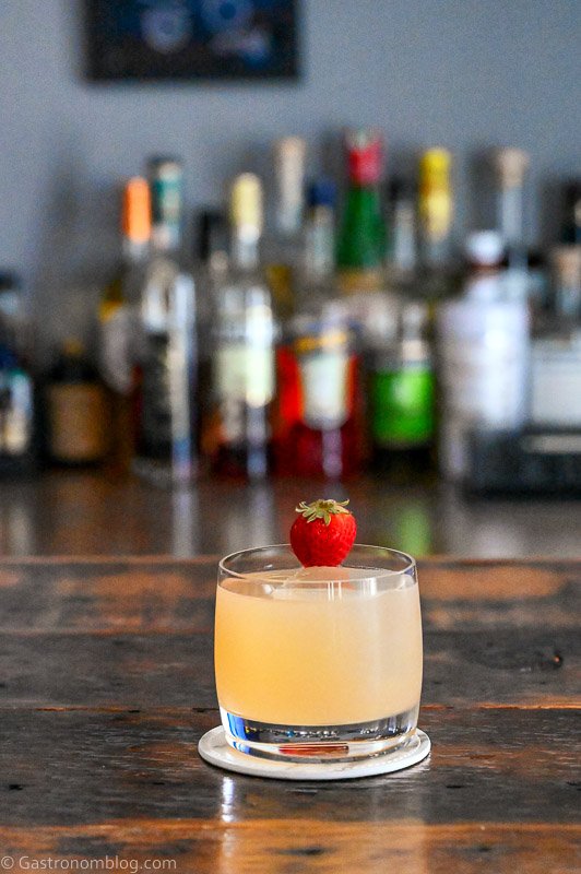 Light Pink strawberry syrup cocktail with whiskey and mezcal with a strawberry garnish