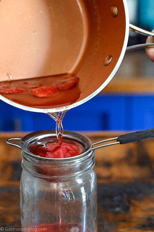 red syrup being poured into a jar from a pot